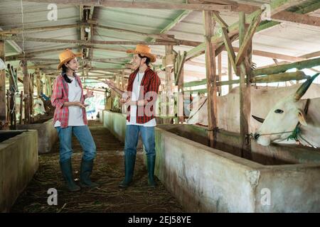 due agricoltori che indossano cappelli da cowboy stanno chiacchierando in piedi bestiame capannone sullo sfondo Foto Stock