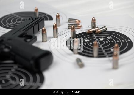 Pistola e molti proiettili che sparano bersagli sul tavolo bianco nel poligono di campo di tiro. Addestramento per la precisione di puntamento e scatto Foto Stock