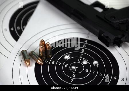 Pistola e molti proiettili che sparano bersagli sul tavolo bianco nel poligono di campo di tiro. Addestramento per la precisione di puntamento e scatto Foto Stock