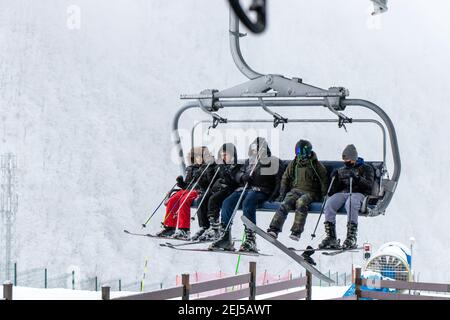 Tufandag, Gabala - Azerbaigian: 30 gennaio 2021. Nevicata. Amici felici sulla sedia di skilift godendo le vacanze invernali di sci in montagna. Foto Stock