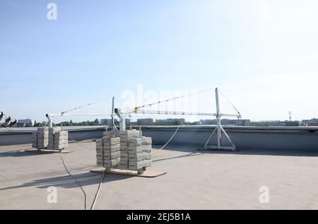 Contrappeso o bilanciamento del peso blocchi di calcestruzzo o mattoni come parte di una piattaforma di funi sospese per lavori di facciata su edifici ad alto livello multipiano. Uomo Foto Stock