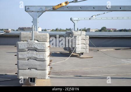 Contrappeso o bilanciamento del peso blocchi di calcestruzzo o mattoni come parte di una piattaforma di funi sospese per lavori di facciata su edifici ad alto livello multipiano. Uomo Foto Stock