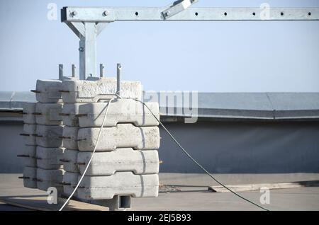 Contrappeso o bilanciamento del peso blocchi di calcestruzzo o mattoni come parte di una piattaforma di funi sospese per lavori di facciata su edifici ad alto livello multipiano. Uomo Foto Stock