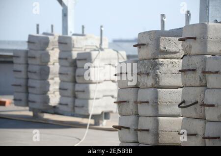 Contrappeso o bilanciamento del peso blocchi di calcestruzzo o mattoni come parte di una piattaforma di funi sospese per lavori di facciata su edifici ad alto livello multipiano. Uomo Foto Stock