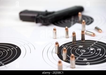 Pistola e molti proiettili che sparano bersagli sul tavolo bianco nel poligono di campo di tiro. Addestramento per la precisione di puntamento e scatto Foto Stock