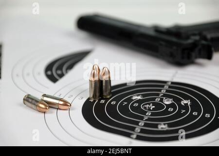 Pistola e molti proiettili che sparano bersagli sul tavolo bianco nel poligono di campo di tiro. Addestramento per la precisione di puntamento e scatto Foto Stock