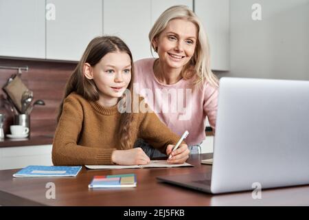 Teen figlia imparante il codice categoria in linea virtuale sulla videochiamata con la mamma a casa. Foto Stock