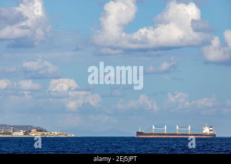 Nave da carico vicino Faro di Capo Peloro a Punta del Faro sullo stretto di Messina, promontorio più a nord-est della Sicilia, Italia Foto Stock