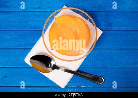 Deliziose pesche sciroppate in un recipiente di vetro su una superficie di Buel. Concetto di cibo di salute. Foto Stock