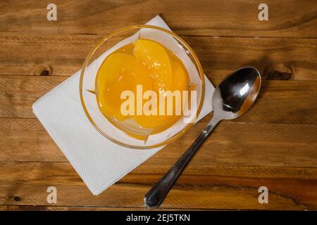 deliziose pesche sciroppate in un recipiente di vetro su una superficie di legno. Concetto di cibo di salute. Foto Stock