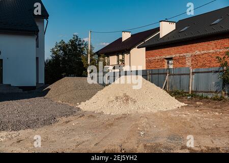 Due cumuli di sabbia bianca con pietre e macerie grigie sul cantiere. Materiale di riempimento. Concetto di base per la costruzione. Foto Stock