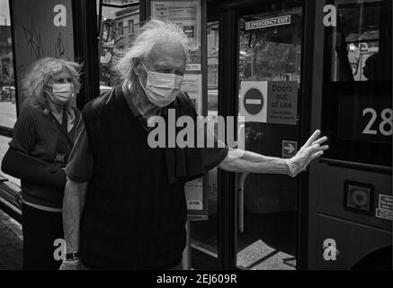 GRAN BRETAGNA / Inghilterra / Londra / UNA coppia più anziana indossando maschere aspetta un autobus a Londra, Inghilterra, il 13 maggio 2020. Foto Stock