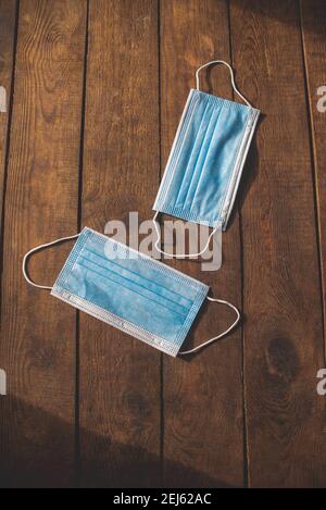 le maschere monouso mediche di protezione in blu giacciono su un legno tabella Foto Stock