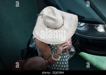 VILLA SAN GIOVANNI, ITALIA - 10 AGOSTO 2016: Vista alta di una donna con cappello di paglia sta bevendo da una bottiglia di plastica di Coca-Cola sostenuta a mano con Foto Stock