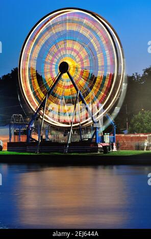 South Elgin, Illinois, Stati Uniti. Una ruota panoramica in un piccolo carnevale estivo della comunità è una macchia di luce. Foto Stock