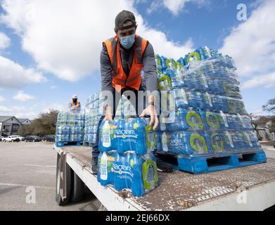 Oak Hill, Texas, Stati Uniti. 21 Feb 2021. I volontari passano fuori i casi di acqua in bottiglia ai disperati residenti della contea occidentale di Travis, Texas, fuori dall'acqua di rubinetto per diversi giorni a causa della devastante tempesta di neve del Texas della scorsa settimana. Gli autisti sono stati autorizzati un solo caso per auto dopo alcune tre ore di attesa il 21 febbraio 2021. Credit: Bob Daemmrich/ZUMA Wire/Alamy Live News Foto Stock