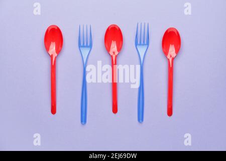 Cucchiai e forcelle in plastica su sfondo colorato Foto Stock