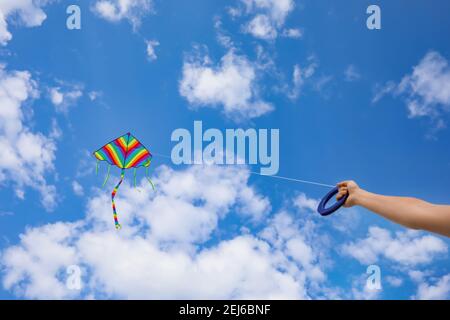 Giovane donna che vola aquilone in cielo blu Foto Stock