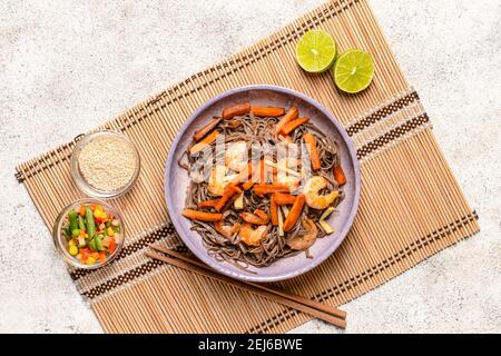 Piatto con gustosi tagliatelle di soba e gamberi su sfondo chiaro Foto Stock