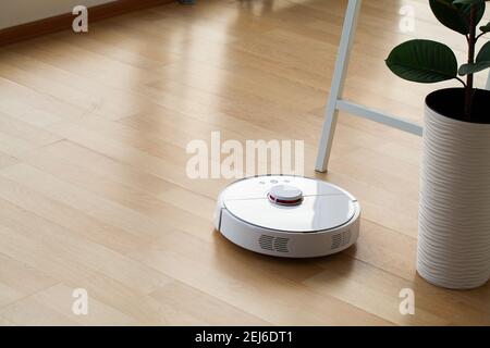 Smart House. Il robot dell'aspirapolvere funziona su pavimenti in legno in ufficio Foto Stock