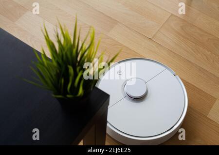 Smart House. Il robot dell'aspirapolvere funziona su pavimenti in legno in ufficio Foto Stock