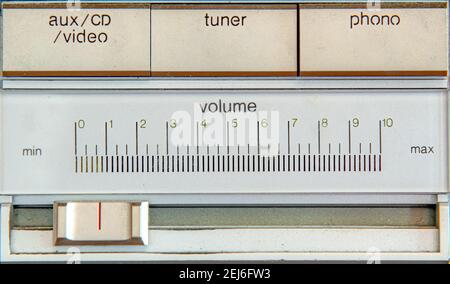 primo piano di alcuni dei comandi di un vecchio sistema stereo. Cursore del volume sotto i controlli di input. Il testo è su metallo spazzolato. Foto Stock