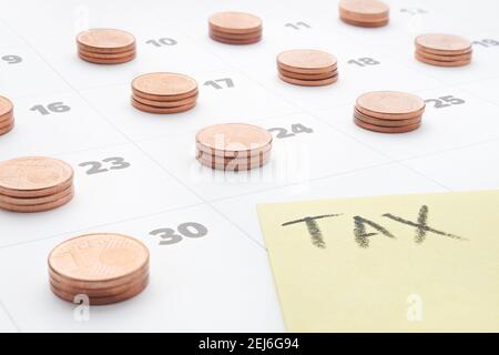 Euro money bilancio di pianificazione fiscale utenze domestiche calendario contabilità fiscale. Tassa di parola scritta su carta gialla con pile di monete in euro l'ultimo giorno Foto Stock
