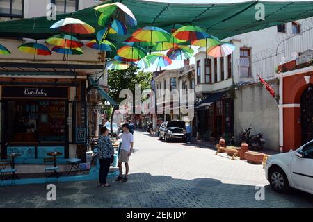 Una scena quotidiana in una strada secondaria di Istanbul, le persone si riuniscono sotto un ombrello baldacchino per chiacchierare mentre vanno per la loro attività. Giugno 2018 Foto Stock