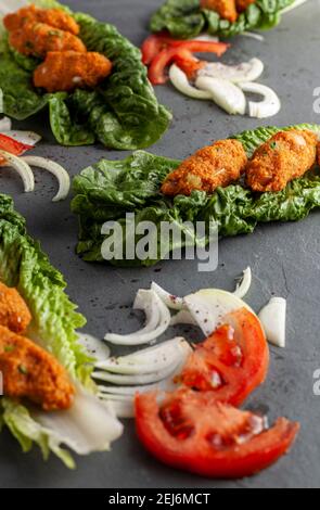 Piatto tradizionale turco a base di bulgaro e lenticchie conosciute come mercimek koftesi (pentola) servita su lattuga verde con cipolla e pomodoro a fette Foto Stock