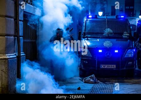 Barcellona, Spagna. 21 Feb 2021. Agenti della Mossos d'Esquadrra, che sorvegliano la sede superiore della polizia della Catalogna camminando attraverso il fumo dei vigili del fuoco, Sulla Vía Laietana durante la manifestazione.Sesta notte di proteste e rivolte in risposta all'arresto e alla detenzione del rapper Pablo Hasel accusato di esalta il terrorismo e di insultare la corona nel contenuto dei testi delle sue canzoni. Credit: SOPA Images Limited/Alamy Live News Foto Stock