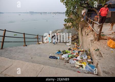 Kolkata, India. 21 Feb 2021. Persone viste alle rive inquinate del fiume Ganga. L'inquinamento idrico è uno dei maggiori problemi ambientali in India per varie ragioni. A Kolkata, ogni volta dopo ogni genere di pujas o festival religiosi, il fiume più santo, il Gange diventa terribilmente inquinato a causa del numero crescente di immersione idolo & spazzatura di leftover. Giorno dopo giorno il Gange sta perdendo la sua capacità di flusso e Kolkata, insieme ai suoi distretti circostanti, si trova a fronteggiare i peggiori problemi di alluvione ogni anno. Credit: SOPA Images Limited/Alamy Live News Foto Stock