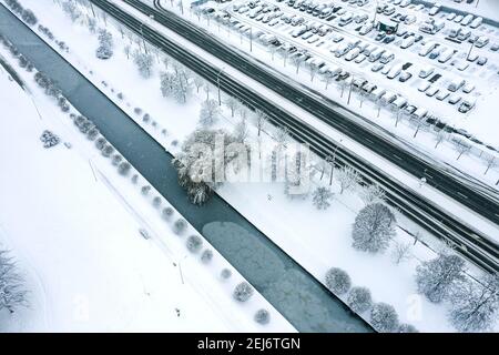 parcheggio vicino al canale d'acqua ghiacciato durante la fredda giornata invernale. vista aerea dall'alto Foto Stock