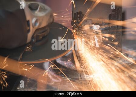 Belle scintille gialle dalla rotazione e taglio del metallo da smerigliatrice manuale come sfondo Foto Stock