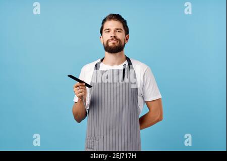 uomo parrucchiere in grembiule grigio forbici pettine barbiere barba folta brunetta Foto Stock