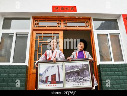 (210222) -- QIANXI, 22 febbraio 2021 (Xinhua) -- Wang Daiyu (L) del gruppo etnico Miao e sua madre Yang Wenmei mostrano le foto delle loro case prima e dopo il trasferimento nel sito di delocalizzazione per le persone colpite dalla povertà nel villaggio di Huawu, nella contea di Qianxi a Bijie, nella provincia di Guizhou, nel sud-ovest della Cina, 20 febbraio 2021. Situato nella profonda area montagnosa di Xinren Miao Township di Guizhou, Huawu Village è famoso per i suoi paesaggi incredibili. Negli ultimi anni, con gli sforzi del governo locale, il villaggio sviluppa la piantagione, la coltivazione e il turismo mentre delocalizza le persone colpite dalla povertà. Nowa Foto Stock