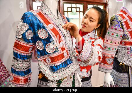 (210222) -- QIANXI, 22 febbraio 2021 (Xinhua) -- Yang Wenli del gruppo etnico Miao organizza costumi Miao nel sito di delocalizzazione per le persone colpite dalla povertà nel villaggio di Huawu, nella contea di Qianxi di Bijie, nella provincia di Guizhou, nel sud-ovest della Cina, 20 febbraio 2021. Situato nella profonda area montagnosa di Xinren Miao Township di Guizhou, Huawu Village è famoso per i suoi paesaggi incredibili. Negli ultimi anni, con gli sforzi del governo locale, il villaggio sviluppa la piantagione, la coltivazione e il turismo mentre delocalizza le persone colpite dalla povertà. Oggi Huawu ha assunto un nuovo look nel nuovo anno, con vari ind Foto Stock