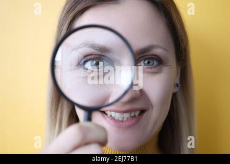 Giovane donna che tiene la lente di ingrandimento vicino al suo occhio Foto Stock