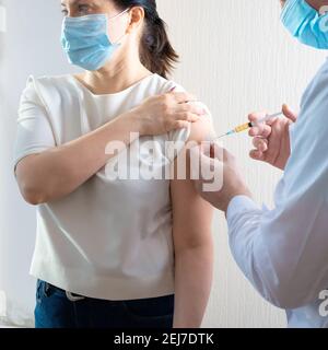 vaccina19. Medico che dà il vaccino Covid alla donna matura.il medico sta iniettando le pazienti di sesso femminile. Donna con maschera viso che si vaccina, corona Foto Stock