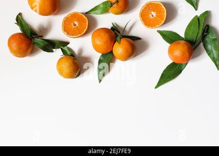 Arance fresche, mandarini. Frutti interi e tagliati con foglie verdi isolate su sfondi bianchi del tavolo. Concetto sano di cibo grezzo. Cornice estiva, web Foto Stock