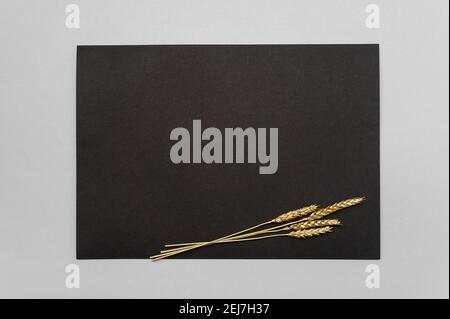 Carta nera di invito mockup con una decorazione d'erba essiccata d'oro su un tavolo neutro. Formato nero Pape 5x7, simile a A3, A4, A5. Spazio di copia minimo Foto Stock