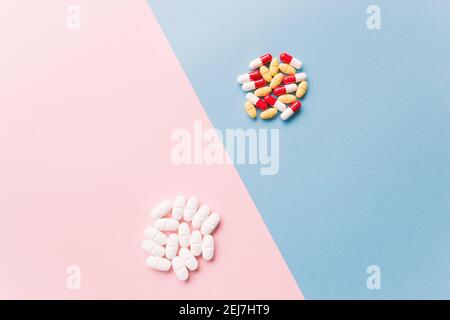 due pile di pillole colorate su un blu e rosa sfondo Foto Stock