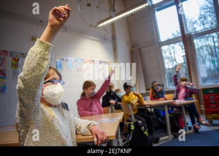Kiel, Germania. 22 Feb 2021. Una studentessa di 4° grado alza la mano in classe alla scuola elementare Russee di Kiel. Nonostante ulteriori restrizioni di contatto per la popolazione nella crisi di Corona, i bambini delle scuole elementari e degli asili dello Schleswig-Holstein visiteranno le rispettive strutture a partire da oggi. Credit: Gregor Fischer/dpa/Alamy Live News Foto Stock