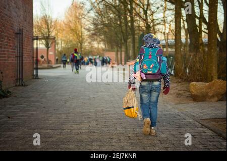 Kiel, Germania. 22 Feb 2021. Un bambino della scuola elementare di Russee a Kiel cammina attraverso il cortile scolastico per classe. Nonostante ulteriori restrizioni di contatto per la popolazione nella crisi di Corona, i bambini delle scuole elementari e degli asili nello Schleswig-Holstein devono frequentare le rispettive istituzioni a partire da oggi. Credit: Gregor Fischer/dpa/Alamy Live News Foto Stock