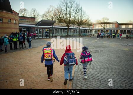 Kiel, Germania. 22 Feb 2021. Gli studenti della scuola primaria Russee a Kiel camminano attraverso il cortile per andare in classe. Nonostante ulteriori restrizioni di contatto per la popolazione nella crisi di Corona, i bambini delle scuole elementari e degli asili nello Schleswig-Holstein devono frequentare le rispettive istituzioni a partire da oggi. Credit: Gregor Fischer/dpa/Alamy Live News Foto Stock