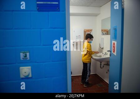 Kiel, Germania. 22 Feb 2021. Un allievo si lava le mani prima della lezione alla scuola primaria Russee di Kiel. Nonostante ulteriori restrizioni di contatto per la popolazione nella crisi di Corona, i bambini delle scuole elementari e degli asili nello Schleswig-Holstein devono frequentare le rispettive istituzioni a partire da oggi. Credit: Gregor Fischer/dpa/Alamy Live News Foto Stock