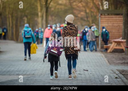 Kiel, Germania. 22 Feb 2021. Una madre porta la sua scolastica nella scuola elementare Russee a Kiel attraverso il cortile scolastico. Nonostante ulteriori restrizioni di contatto per la popolazione nella crisi di Corona, gli alunni delle scuole elementari e i bambini degli asili nello Schleswig-Holstein visiteranno le rispettive strutture a partire da oggi. Credit: Gregor Fischer/dpa/Alamy Live News Foto Stock