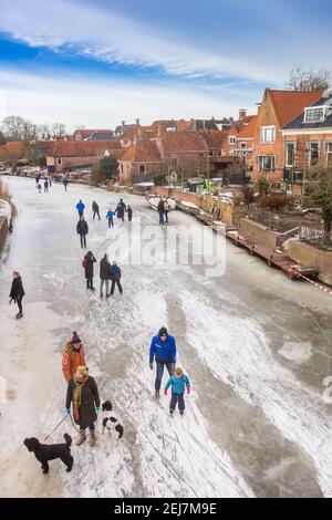 Persone che camminano i loro cani sul fiume congelato a Winsum, Paesi Bassi Foto Stock