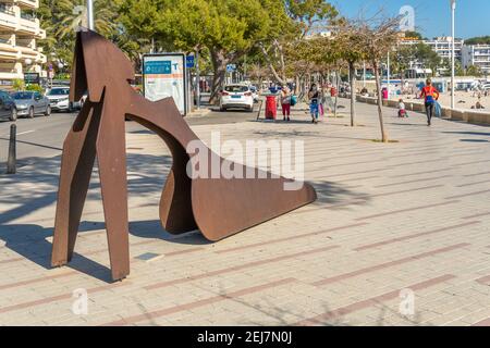 Palmanova, Spagna; febbraio 20 2021: Passeggiata marittima della località turistica maiorchina di Palmanova, con una scultura in ferro. Pedoni a piedi Foto Stock