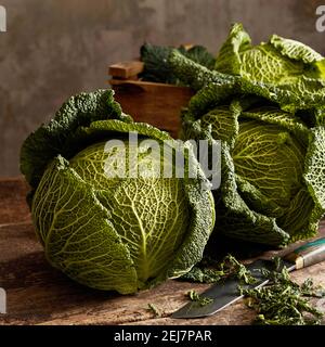 Gustose teste di cavolo sabaudo in scatola di legno sul tavolo con coltello in studio Foto Stock