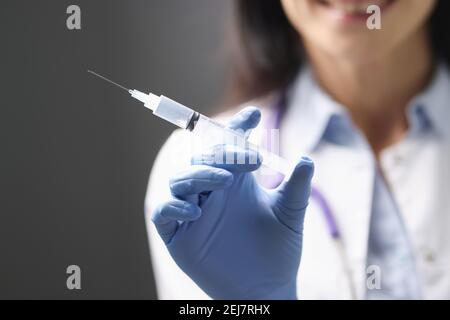 I medici mano nel guanto di gomma che tiene la siringa con il closeup del medicinale Foto Stock